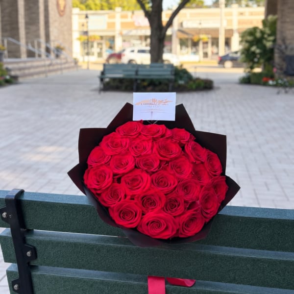 Bouquet of red roses wrapped in dark paper with a card attached