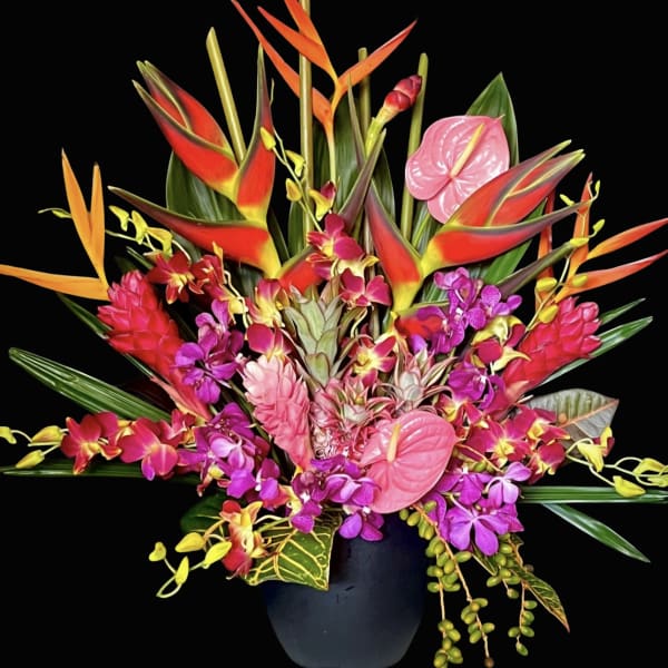 Tropical flower arrangement in a black vase with pink anthuriums and orchids