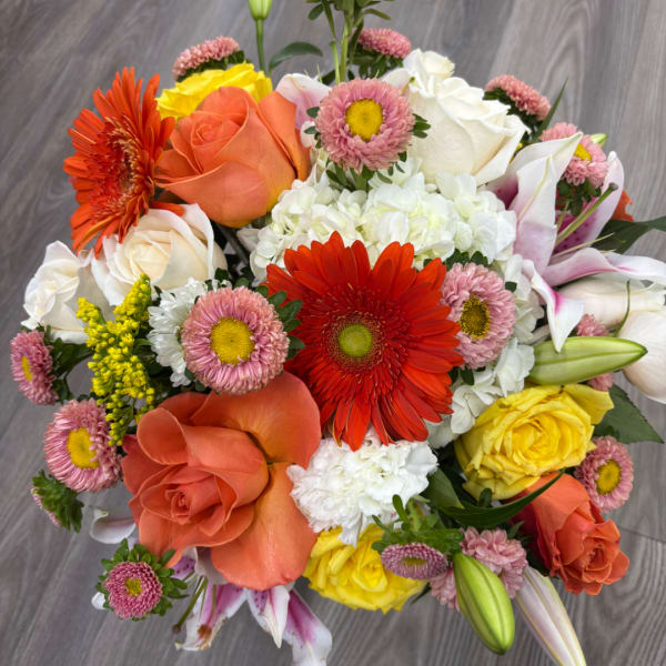 Mixed bouquet with orange and yellow roses, gerbera daisies, lilies, and pink daisies