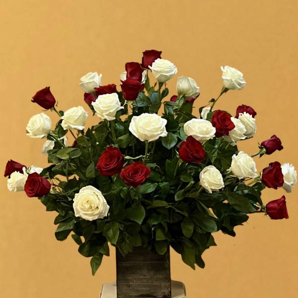 Red and white roses arranged in a tall vase on a pedestal