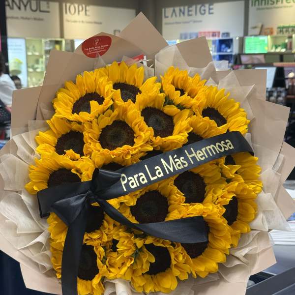 Bouquet of yellow sunflowers wrapped in beige paper with a black ribbon