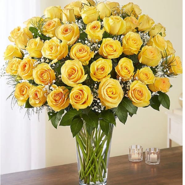 Yellow roses arranged in a clear glass vase on a table