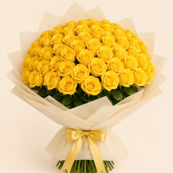 Large bouquet of yellow roses wrapped in cream paper with a gold ribbon
