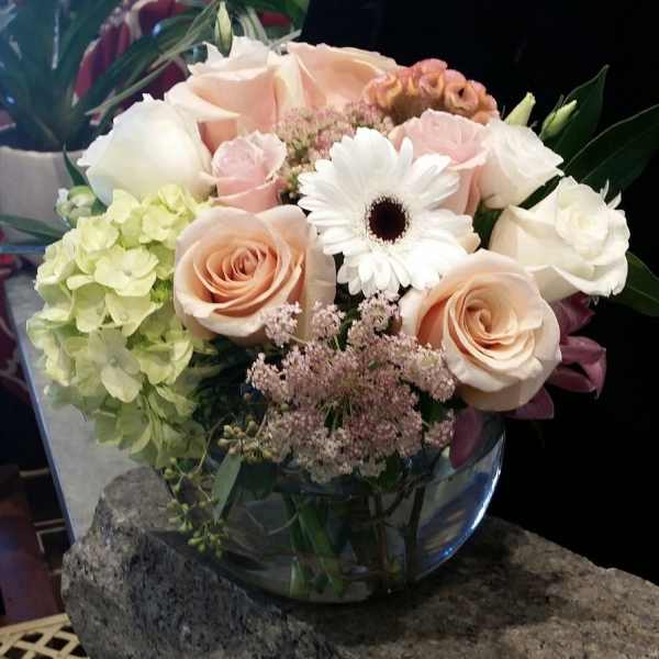 Bouquet of pale roses, hydrangea, and a white gerbera daisy in a glass vase