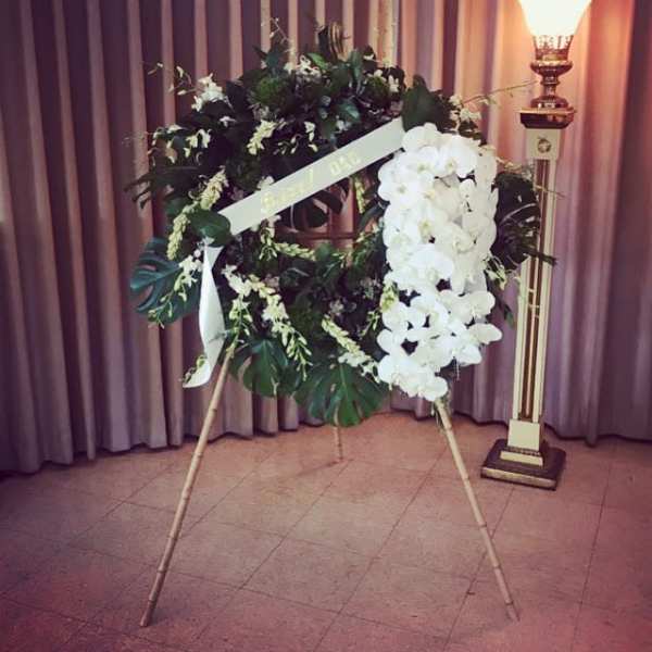 White floral funeral wreath on a stand with a ribbon