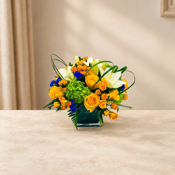 Yellow and white flower arrangement in a square glass vase