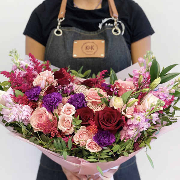 Large bouquet of pink, red, and purple flowers wrapped in pink paper