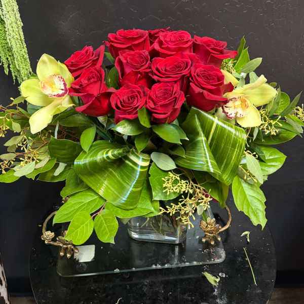 Red roses with pale yellow orchids in a glass vase