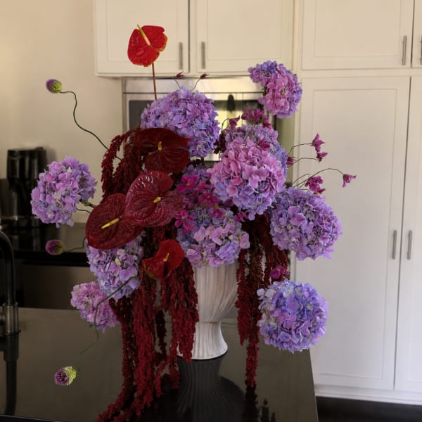 Purple hydrangeas with red anthuriums in a white vase