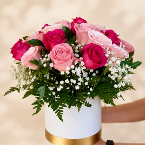 Pink and hot pink roses in a white round box with baby's breath