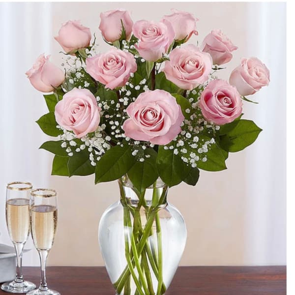 Pink roses arranged in a clear glass vase with white filler flowers
