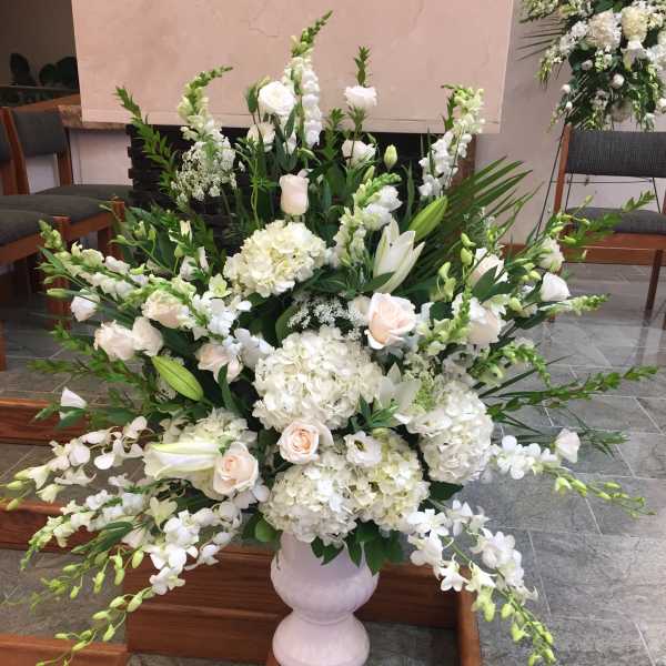 Large white floral arrangement in a pale vase