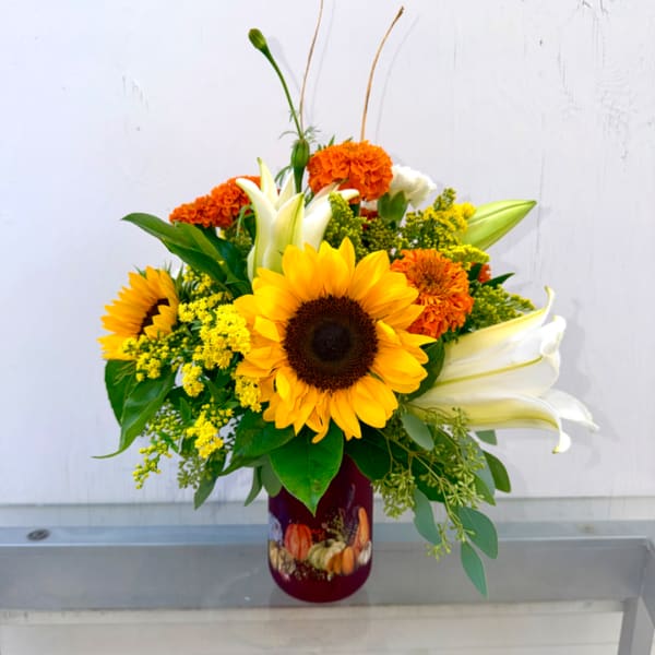 Sunflower and lily arrangement in a burgundy vase