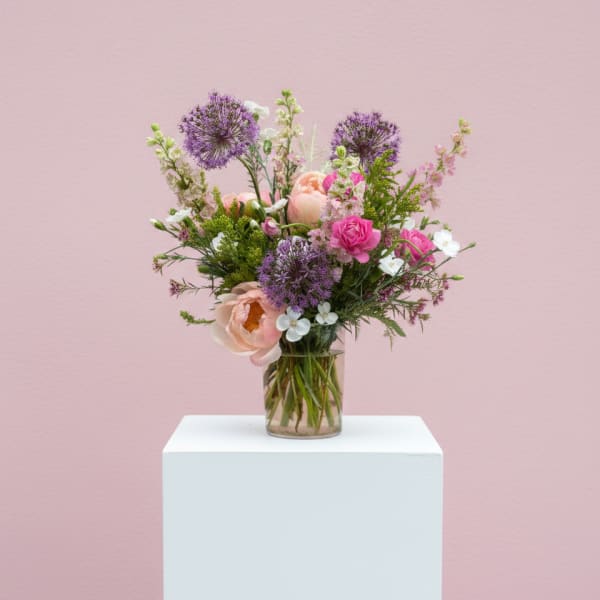 Mixed bouquet of pink and purple flowers in a clear glass vase
