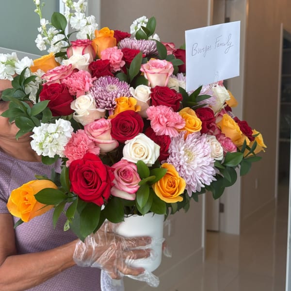 Large mixed bouquet of roses, carnations, and chrysanthemums in a white vase