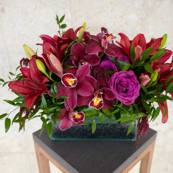 Magenta and red floral arrangement in a rectangular glass vase