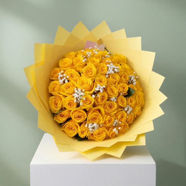 Bouquet of yellow roses with white filler flowers in yellow wrap