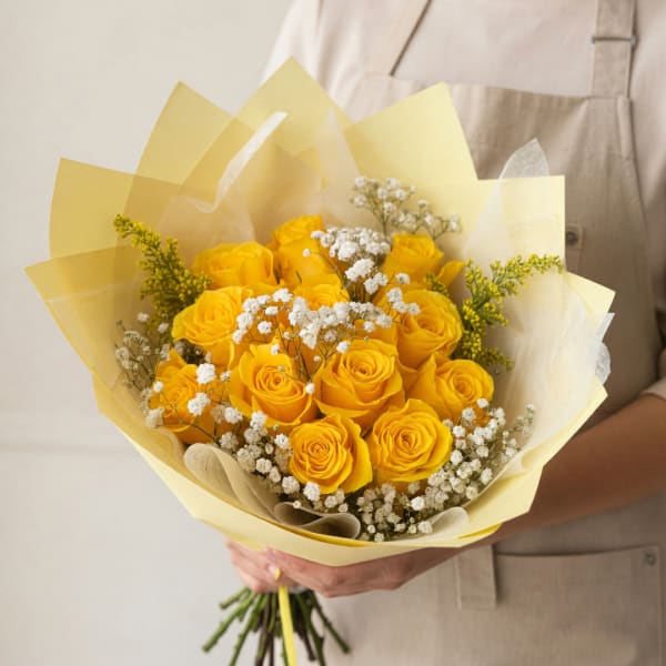 Bouquet of yellow roses with white baby's breath in pale yellow wrap