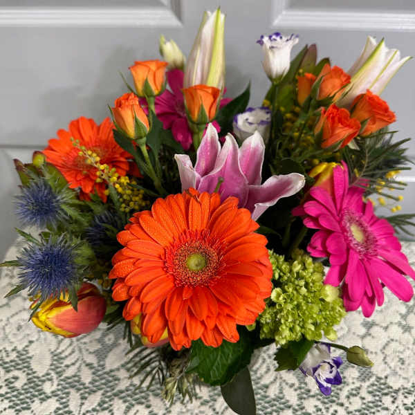 Bright mixed bouquet with orange gerberas, roses, lilies, and pink blooms