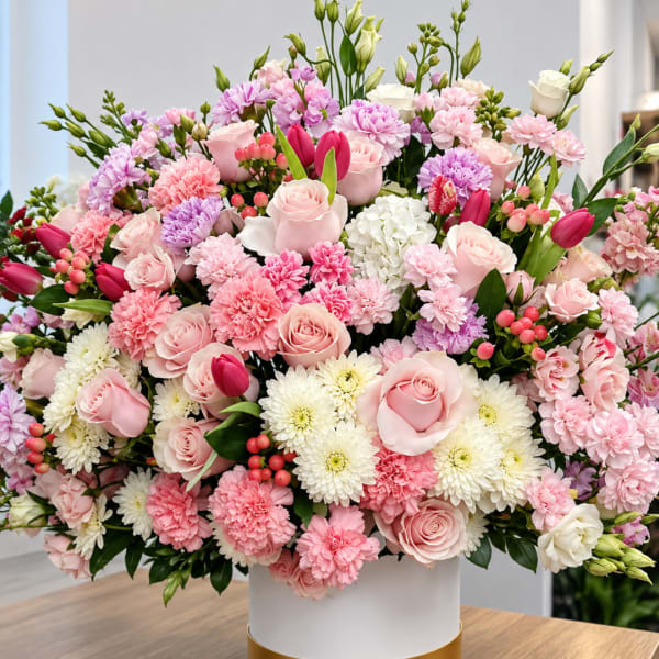 Large pink and white floral arrangement in a white vase