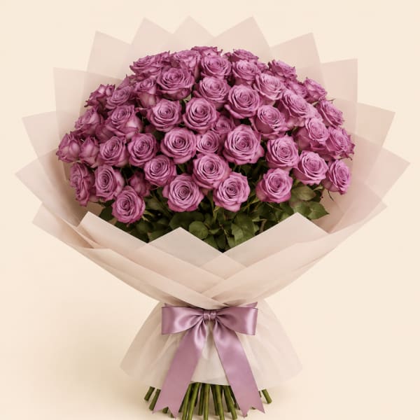 Large bouquet of purple roses wrapped in pale paper with a satin ribbon