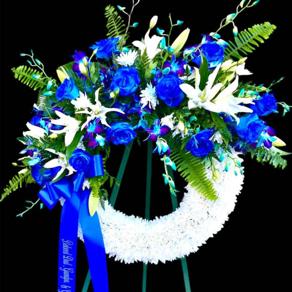 Blue and white funeral wreath on a stand with a ribbon