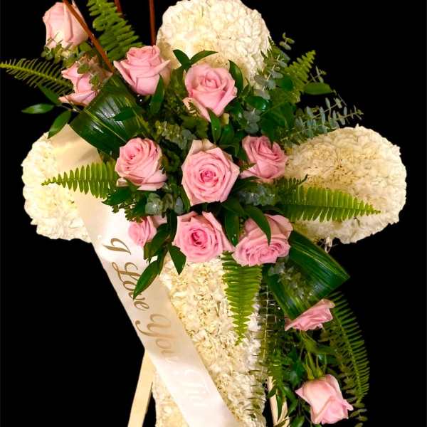 Pink roses and white flowers arranged on a standing easel with a sash