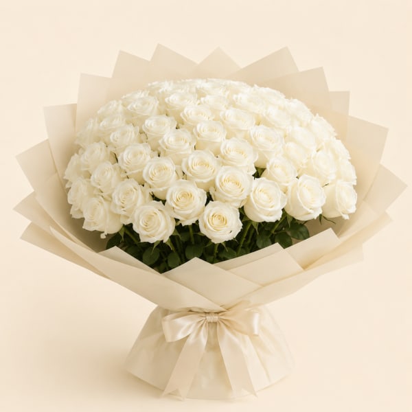 Large bouquet of white roses wrapped in cream paper with a satin bow