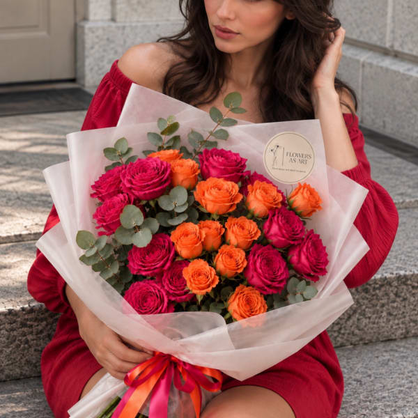 Bouquet of hot pink and orange roses wrapped in pale paper
