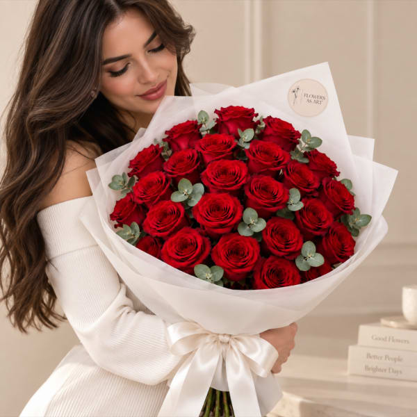 Woman holding a bouquet of red roses wrapped in white paper with a satin bow.