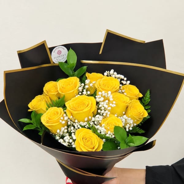 Bouquet of yellow roses with white baby's breath in black wrap