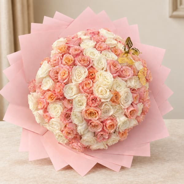 Round bouquet of pink and white roses wrapped in pale pink paper