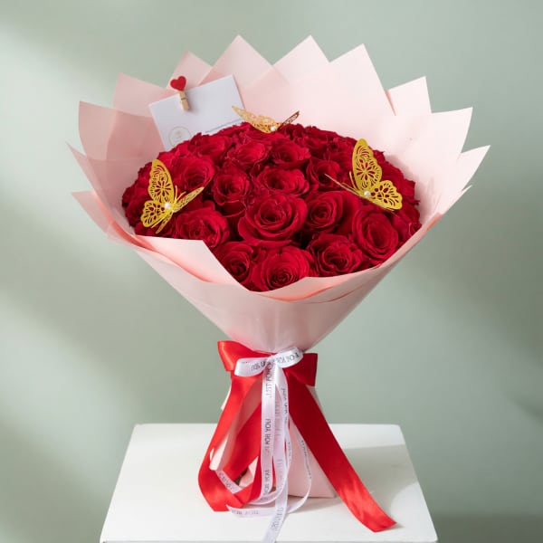 Bouquet of red roses wrapped in pink paper with a red ribbon