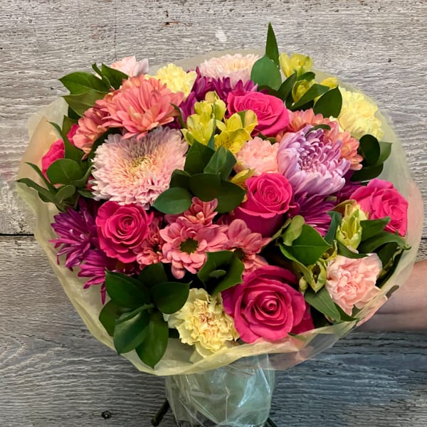 Bouquet of pink roses, chrysanthemums, and alstroemeria wrapped in pale paper