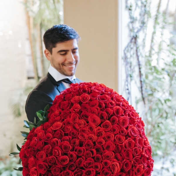 Man holding a large bouquet of red roses
