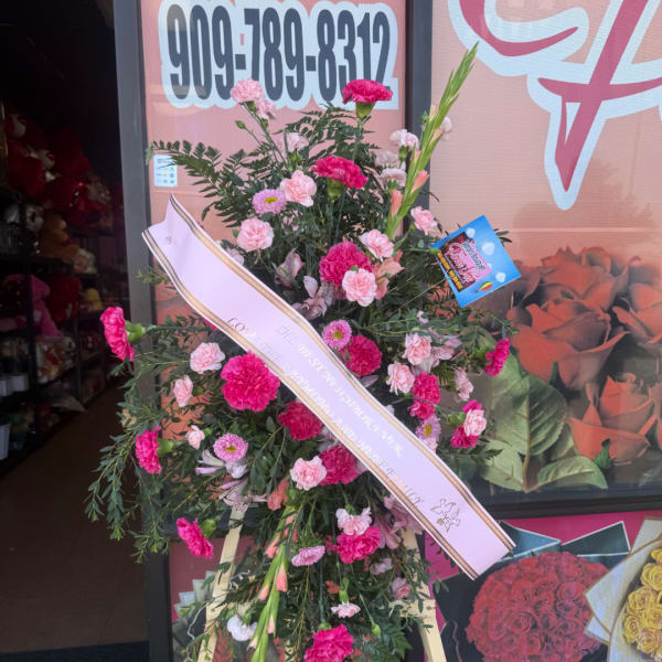 Pink and white floral standing spray with a ribbon on an easel