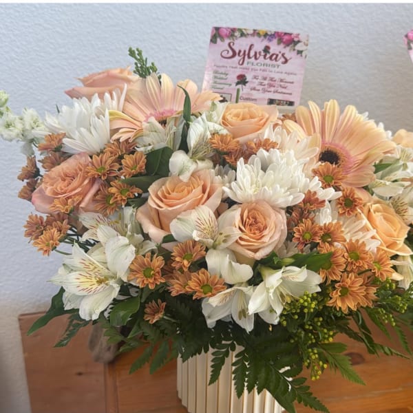 Peach roses and white daisies in a white vase