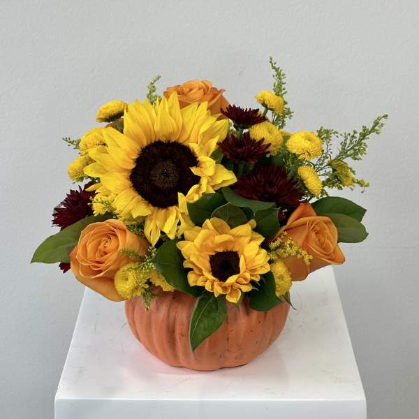 Sunflowers and orange roses in a pumpkin-shaped container