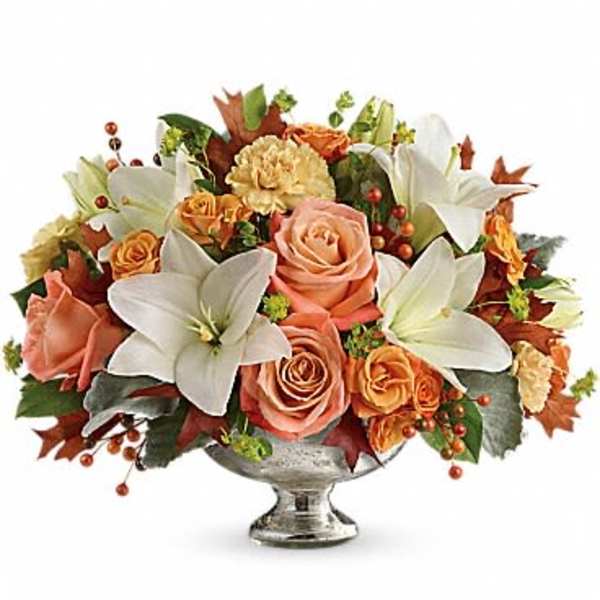 Peach roses and white lilies arranged in a silver pedestal vase