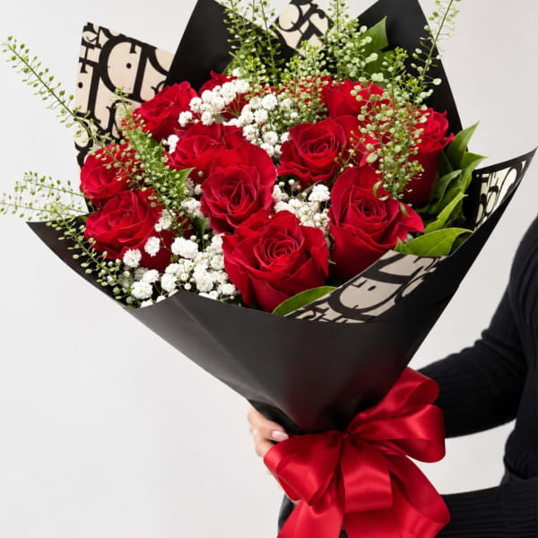 Bouquet of red roses with white baby's breath in black wrap and a red ribbon