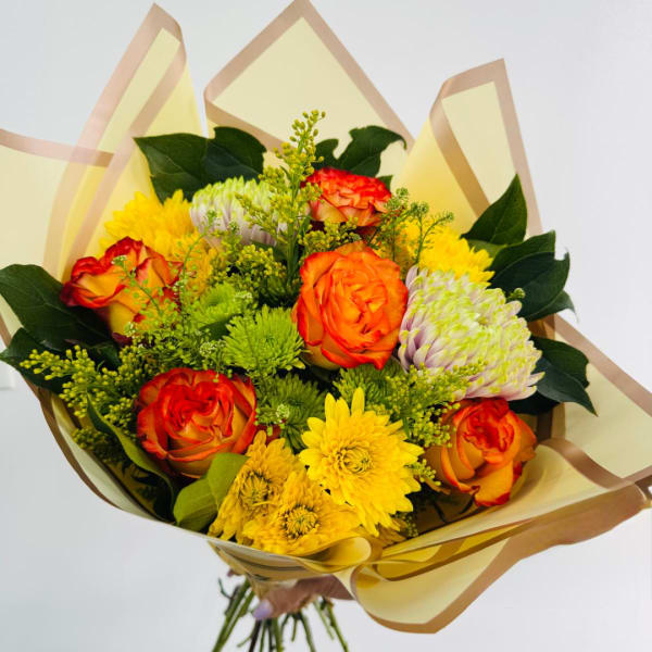 Bouquet of orange roses and yellow chrysanthemums wrapped in pale paper