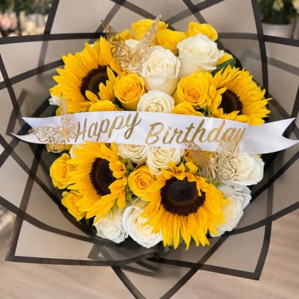 Bouquet of yellow sunflowers and white roses with a Happy Birthday ribbon