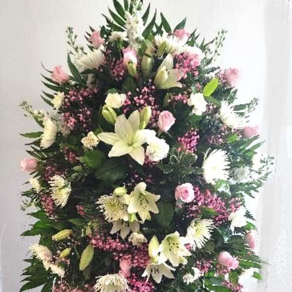 Tall standing floral spray with pink and white flowers on a black easel