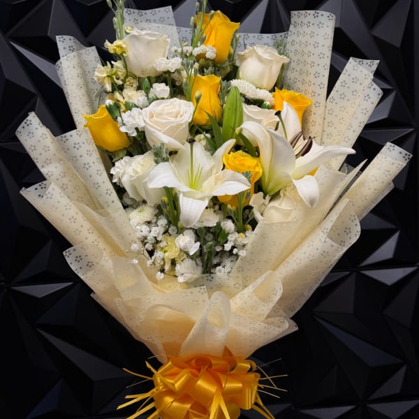 Bouquet of white and yellow roses with white lilies wrapped in patterned paper