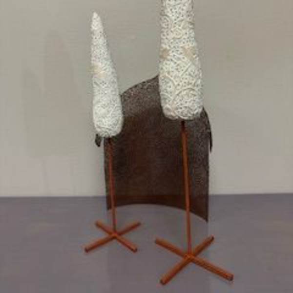 Two white cone-shaped decorative pieces on stands beside a brown panel