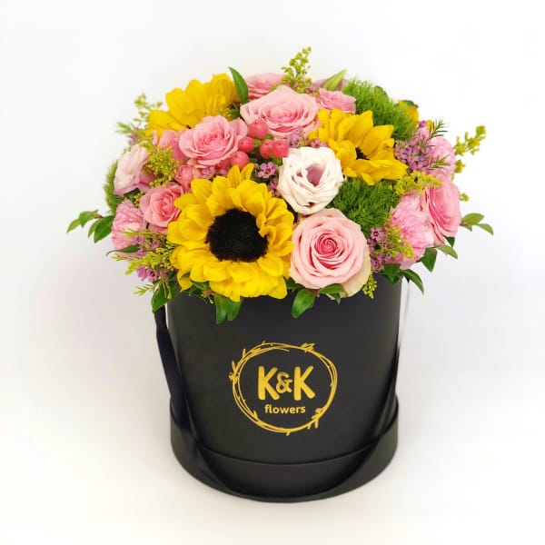 Pink roses and yellow sunflowers in a black hatbox