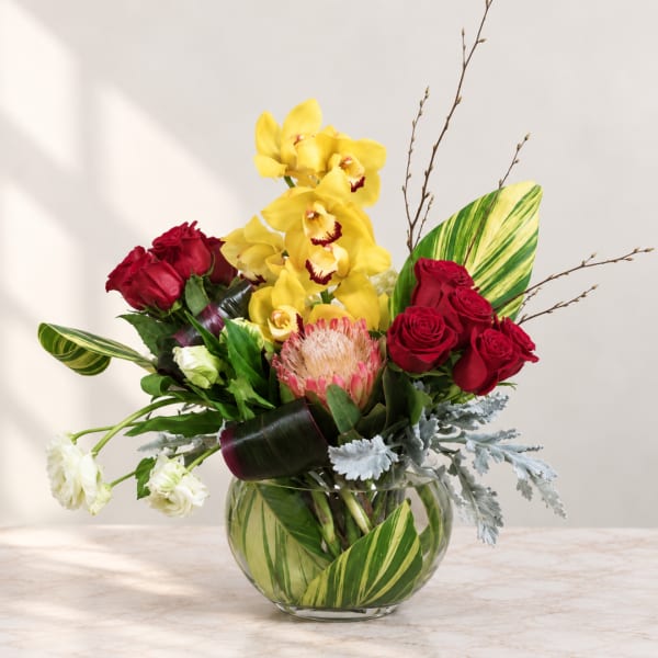 Bouquet of red roses and yellow orchids in a glass vase