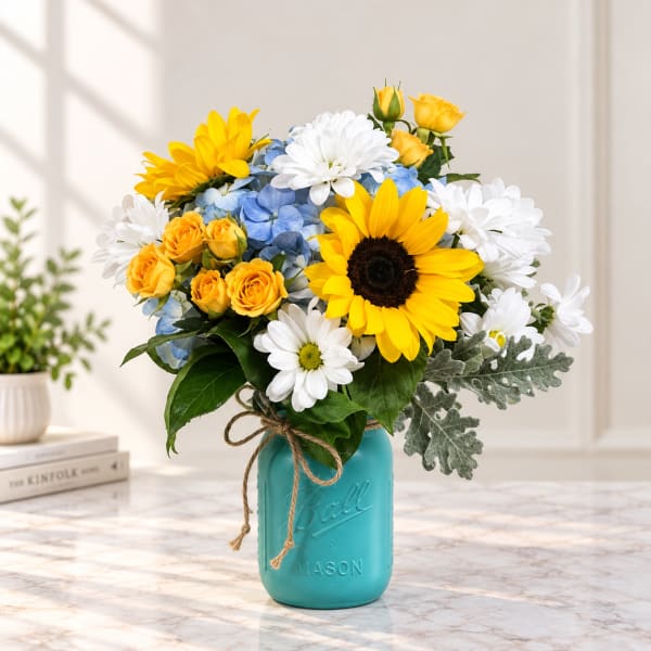 Bouquet of yellow sunflowers, white daisies, blue hydrangeas, and yellow roses in a turquoise mason jar