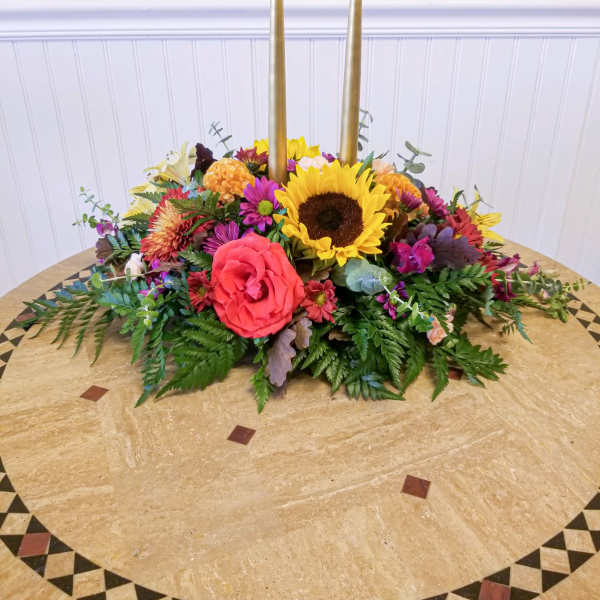 Colorful floral centerpiece with two tall gold candles