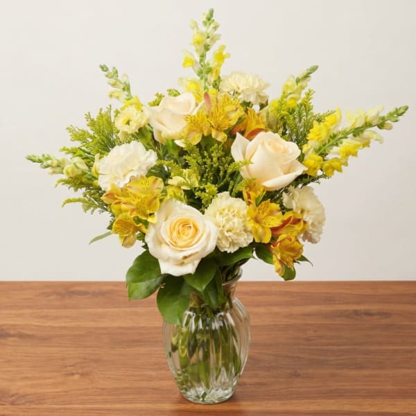 Yellow and white flower bouquet in a clear glass vase